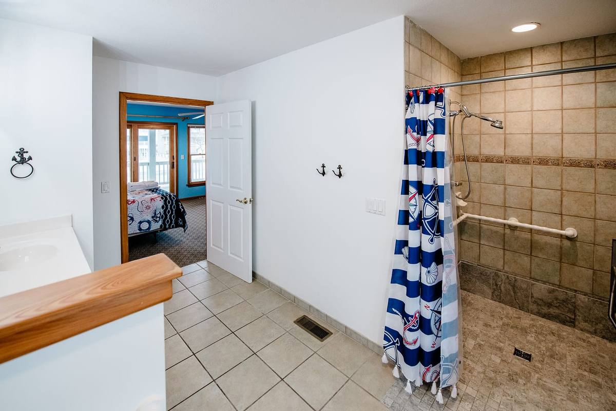 Bathroom looking toward the bedroom door, with a towel ring and shower