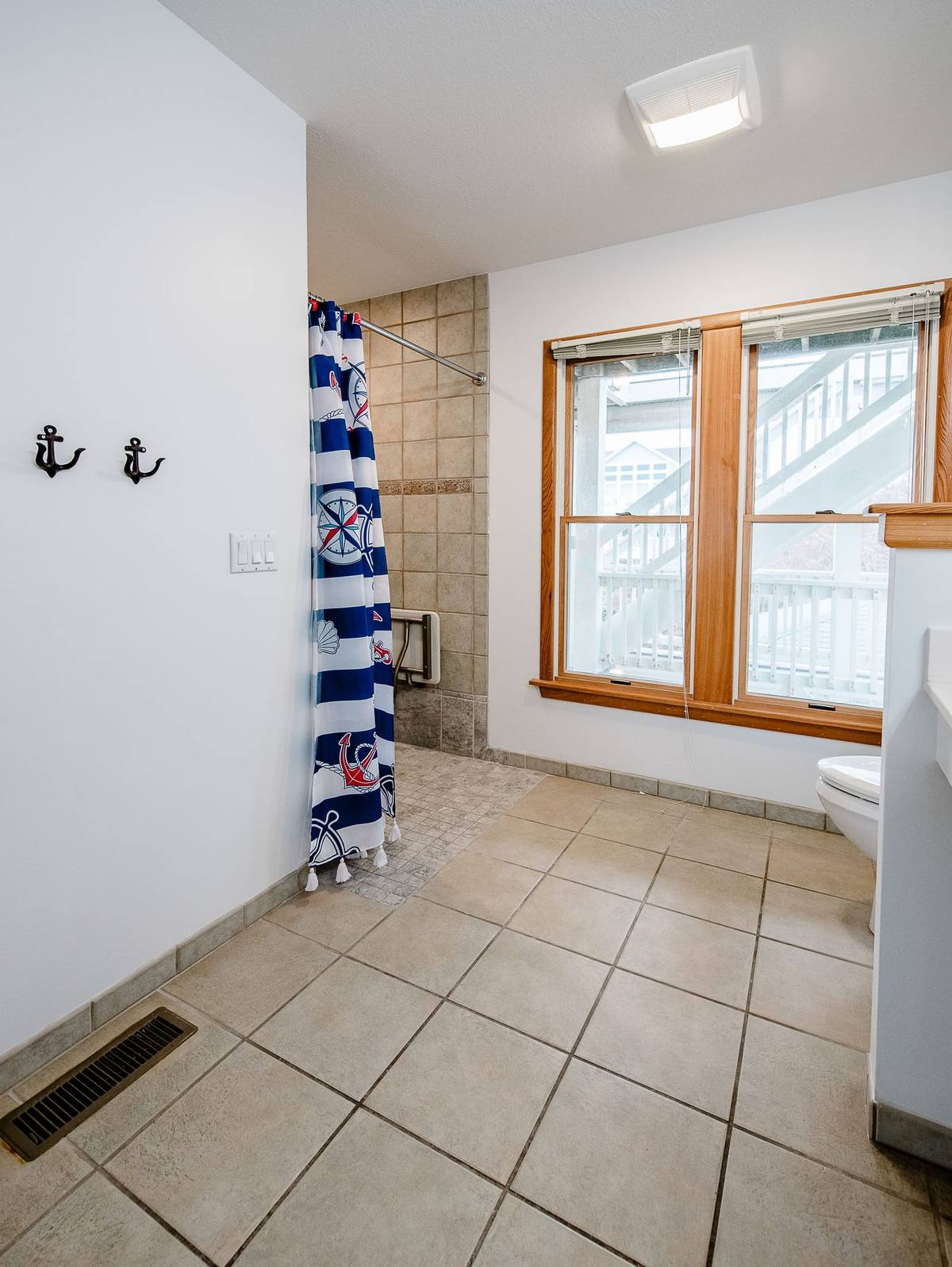 Bathroom wall with anchor hooks beside a curtain-covered accessible shower