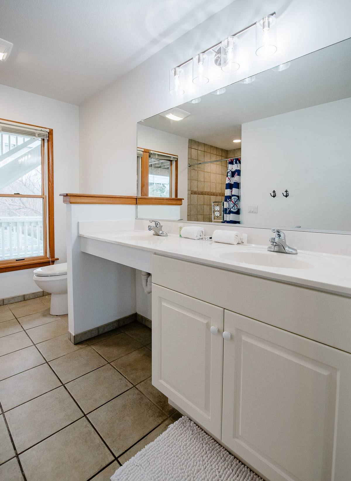 Wide bathroom vanity with a mirror reflecting the shower curtain