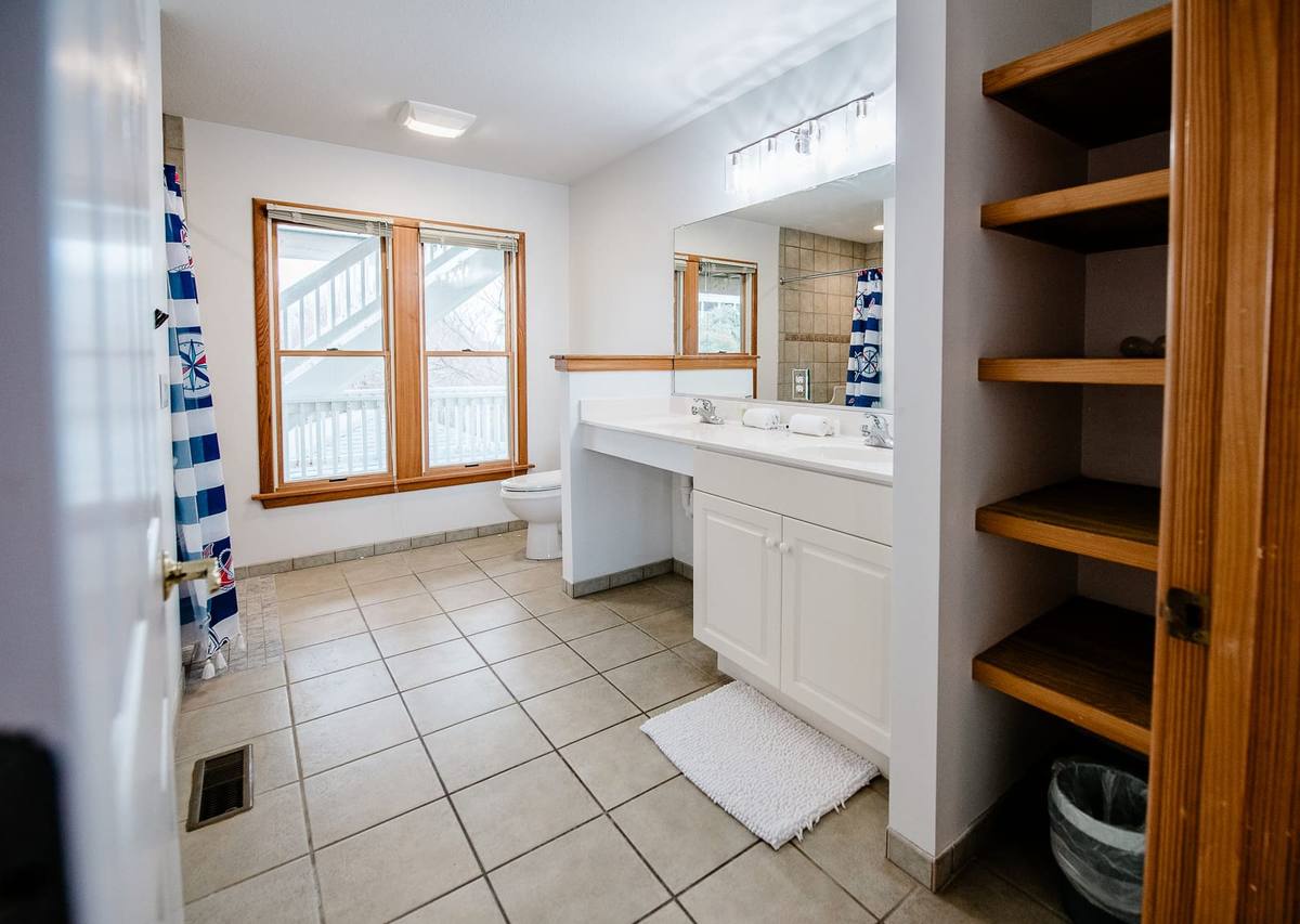 Bathroom with a double vanity, built-in shelves, and a tile floor