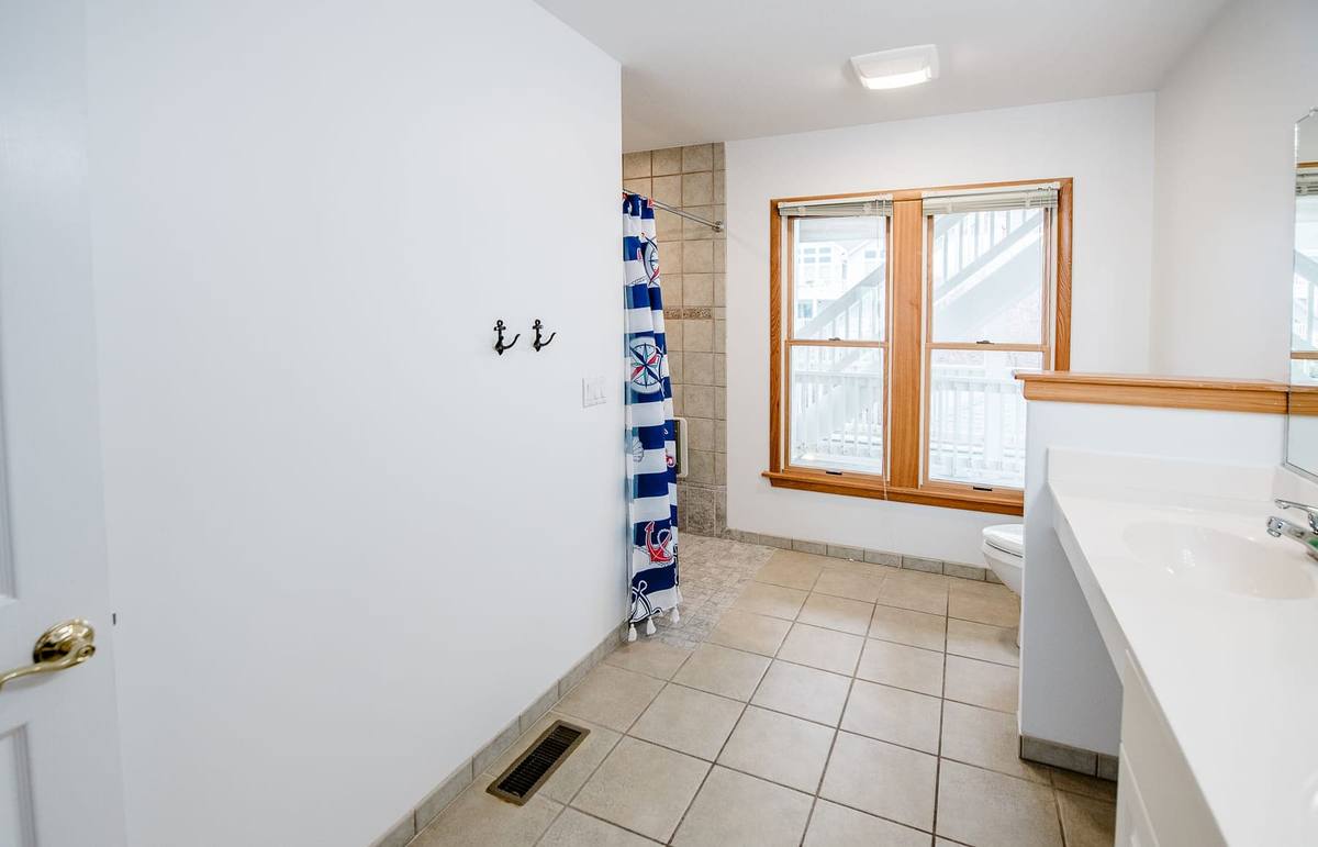Bathroom with a window, tile floor, and a striped nautical shower curtain