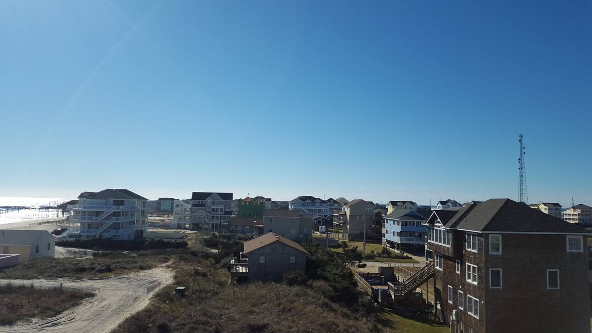 An elevated view over a Corolla beach neighborhood of houses toward the ocean