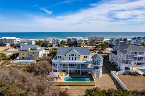 Aerial view of the house from the ocean side, showing the roofline and proximity to the beach