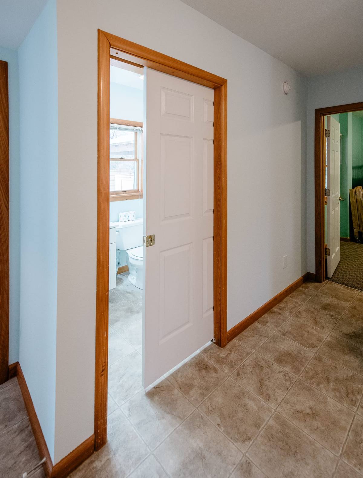 Hallway leading to a bathroom, with the game room reflected in the mirror