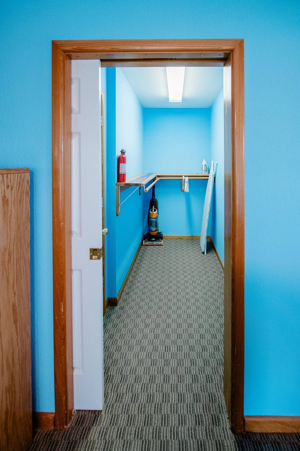 Walk-in closet with a hanging rod, shelf, and an ironing board and a vacuum