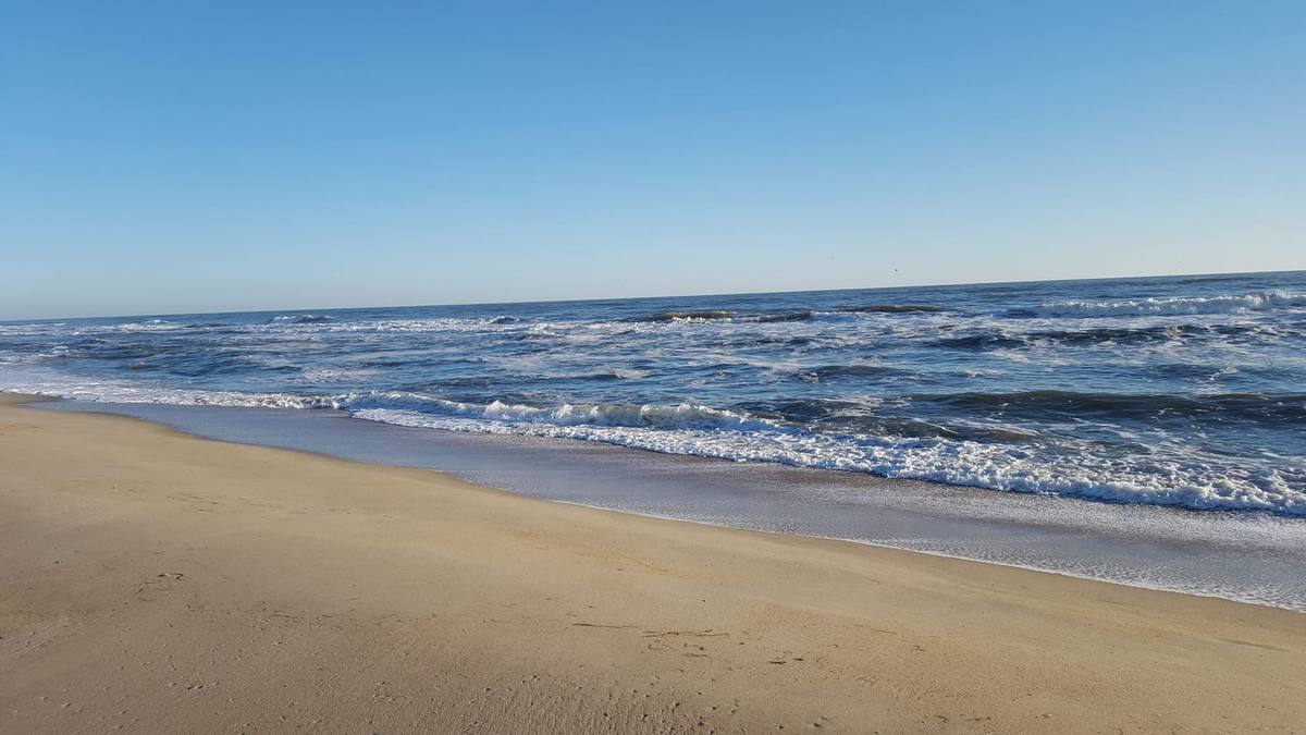 Blue Atlantic surf breaking along an empty beach on a clear morning
