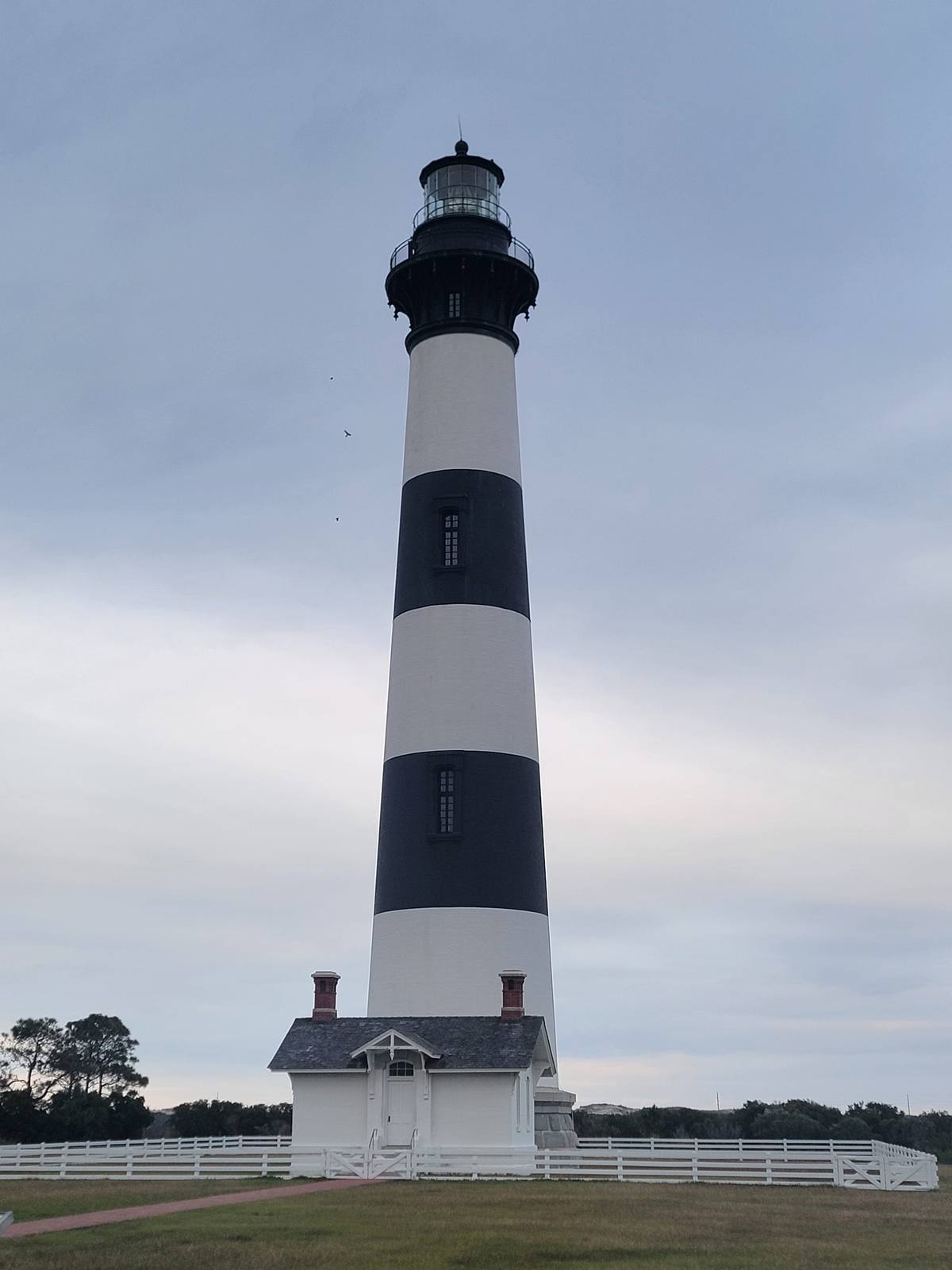 The black-and-white banded Bodie Island Lighthouse rising into a cloudy sky