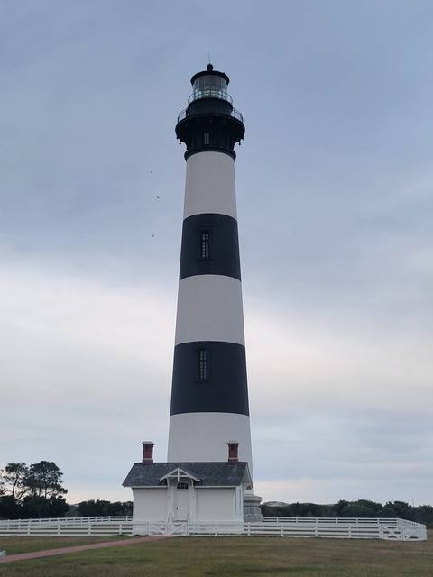 The black-and-white banded Bodie Island Lighthouse rising into a cloudy sky