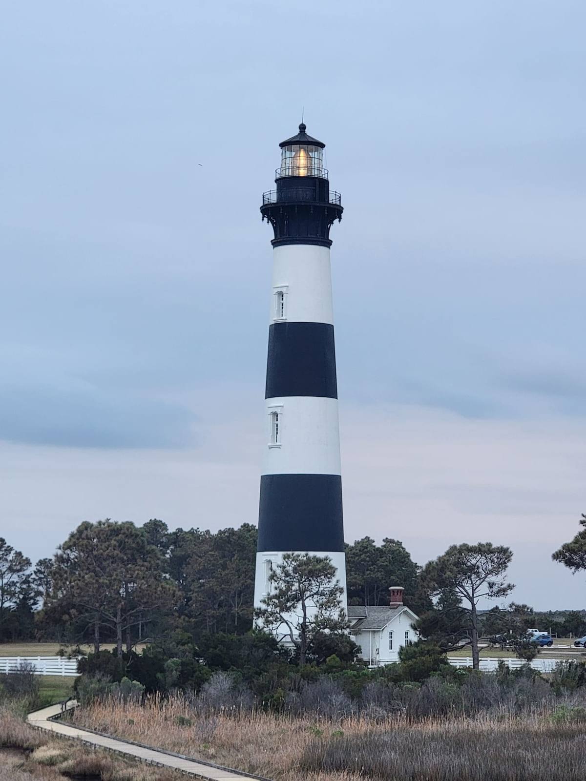 The black-and-white banded Bodie Island Lighthouse rising above the trees