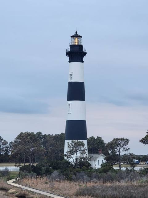 The black-and-white banded Bodie Island Lighthouse rising above the trees