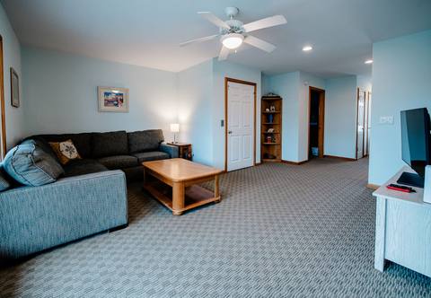 Den with a gray sectional, coffee table, and TV under a ceiling fan
