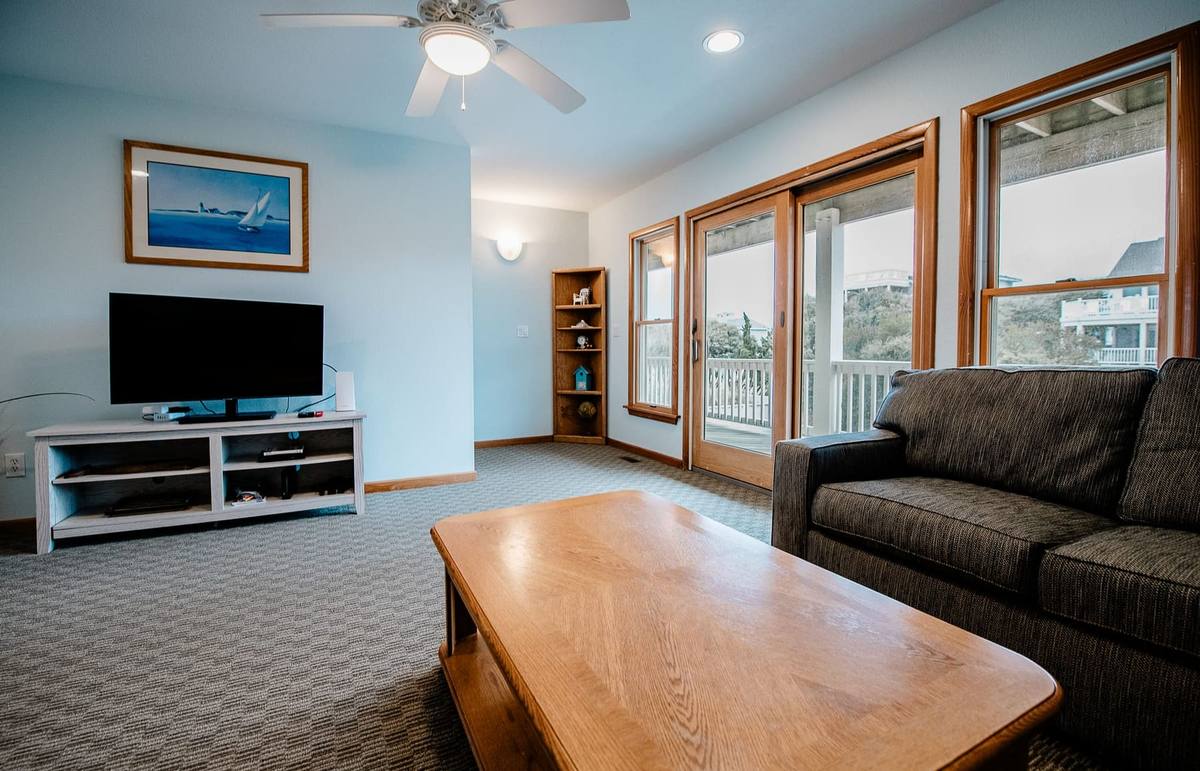 Den with a TV, sofa, and sliding doors to the deck