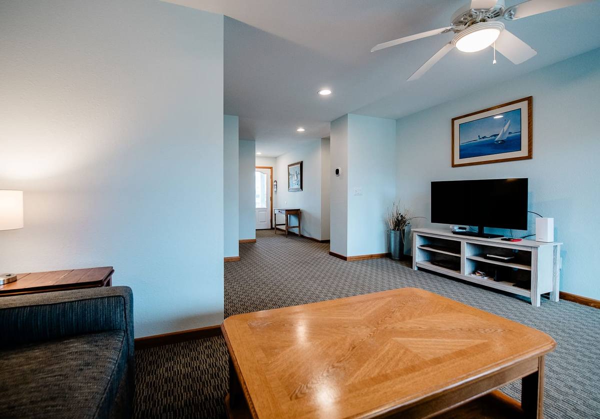 Wide view of the den with a sofa, coffee table, TV, and hallway beyond