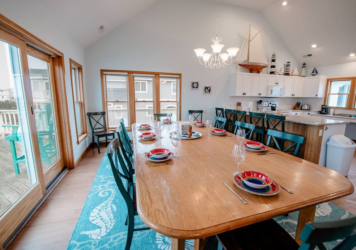 Long dining table set for a large group with the kitchen visible behind it