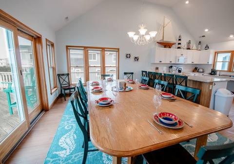 Long dining table set for a large group with the kitchen visible behind it