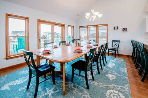 Long dining table set for a large group on a coastal rug