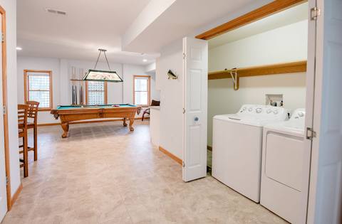 Lower-level game room with a pool table, a stained-glass lamp, and a washer and dryer