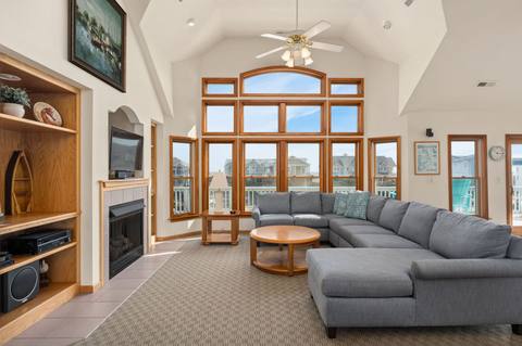 Open top-level great room with vaulted ceiling, large windows, and comfortable seating for a full house