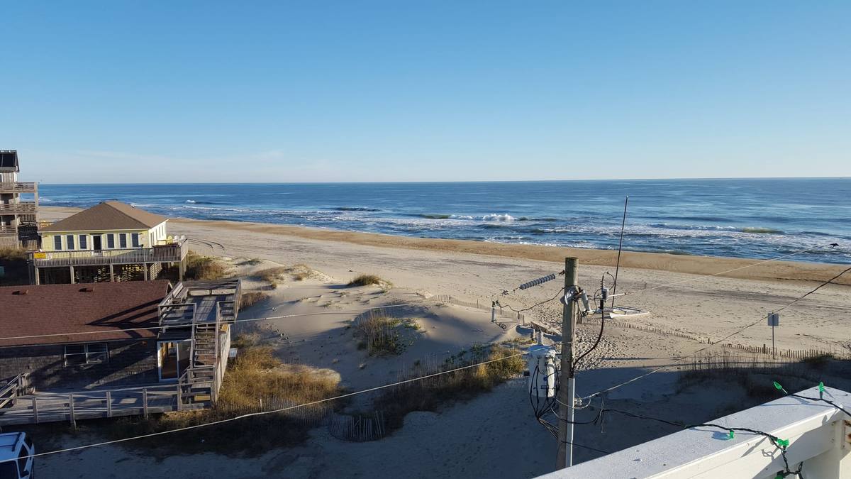 Beach houses on stilts rising above dune grass with the ocean beyond