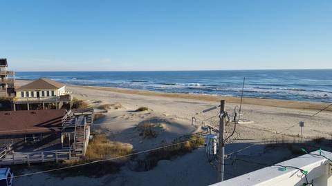 Beach houses on stilts rising above dune grass with the ocean beyond