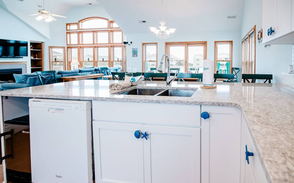 Kitchen island with a dishwasher and sink and the living room behind it