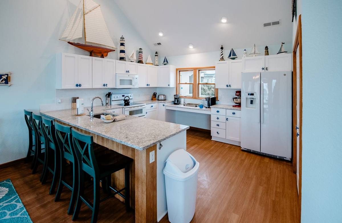 Kitchen island with teal bar stools and a stainless refrigerator