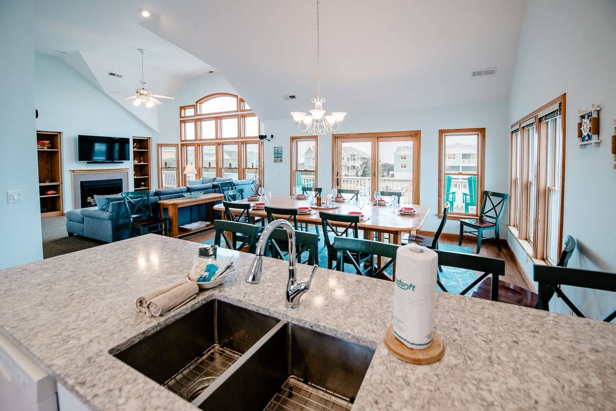Double stainless sink in the kitchen island with the dining table and living room beyond
