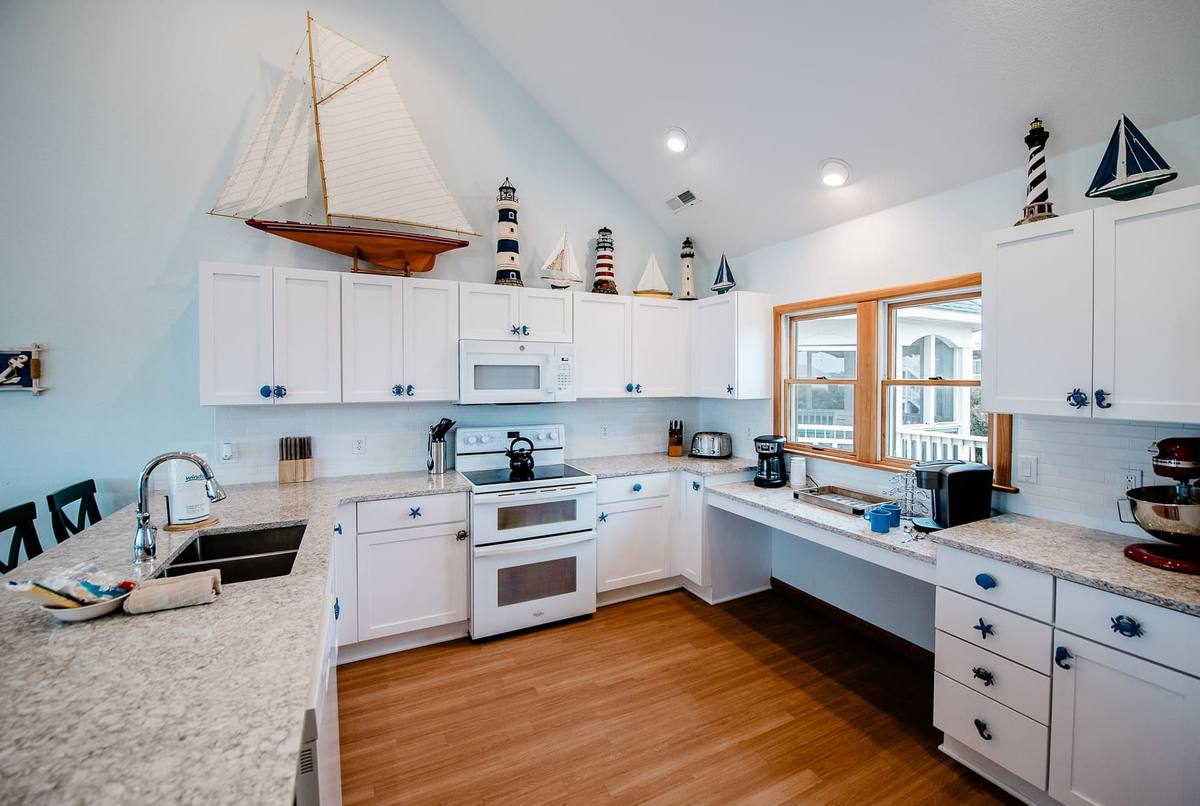 Kitchen with white cabinets, granite counters, a double oven, and a model sailboat above the cabinets