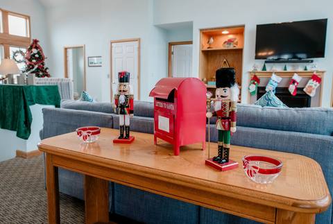 Two nutcracker figures stand watch over a red Letters to Santa mailbox on a console table, with the decorated tree and stocking-hung mantle visible behind