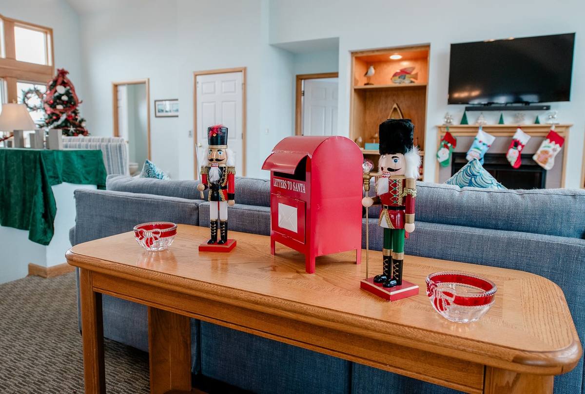 Two nutcracker figures stand watch over a red Letters to Santa mailbox on a console table, with the decorated tree and stocking-hung mantle visible behind