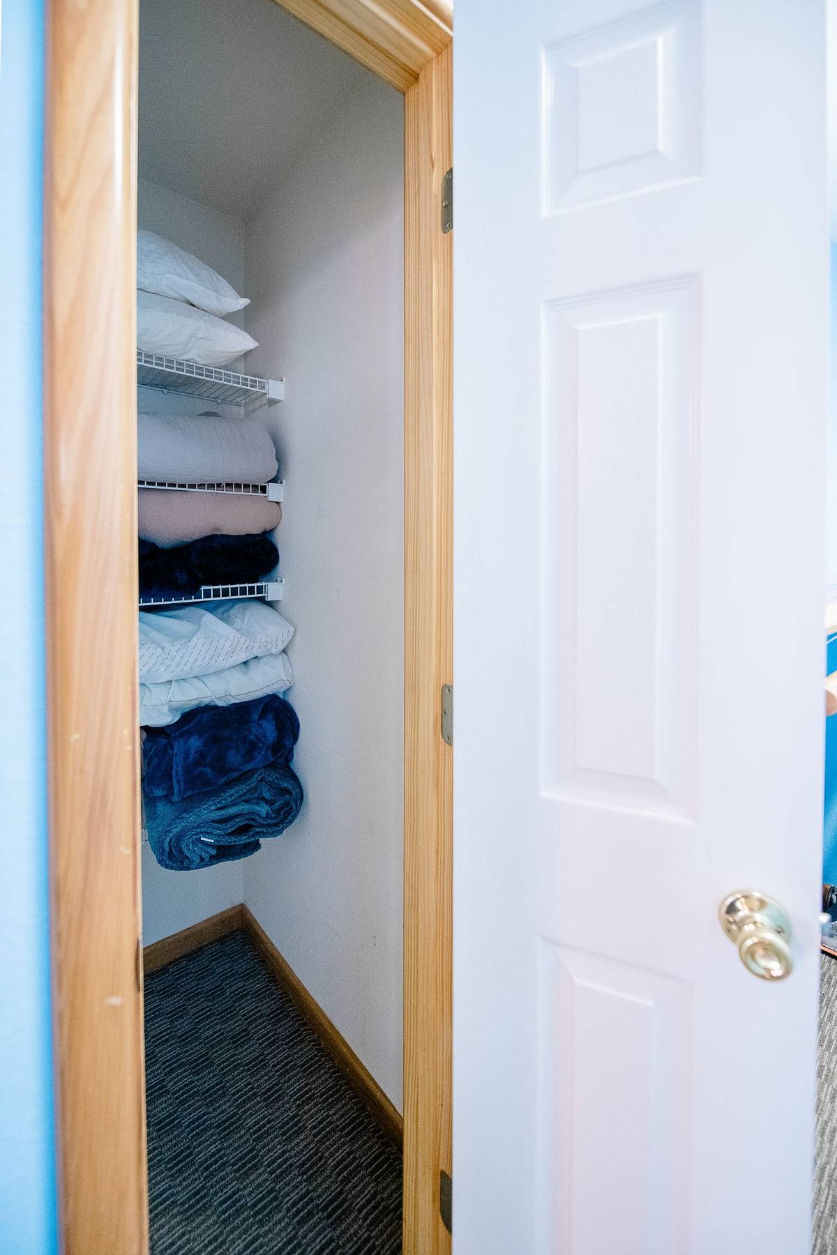 Shelves of folded blankets and towels in a linen closet