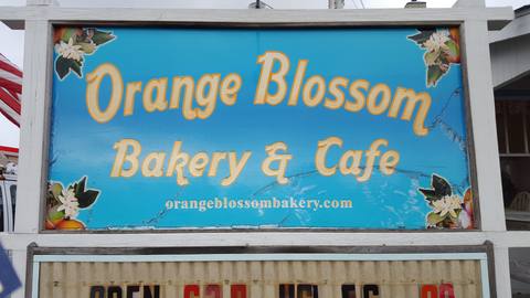 A hand-painted blue sign for the Orange Blossom Bakery & Cafe