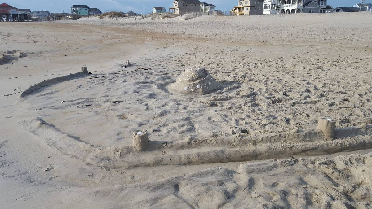 A small hand-built sandcastle close up on an empty beach