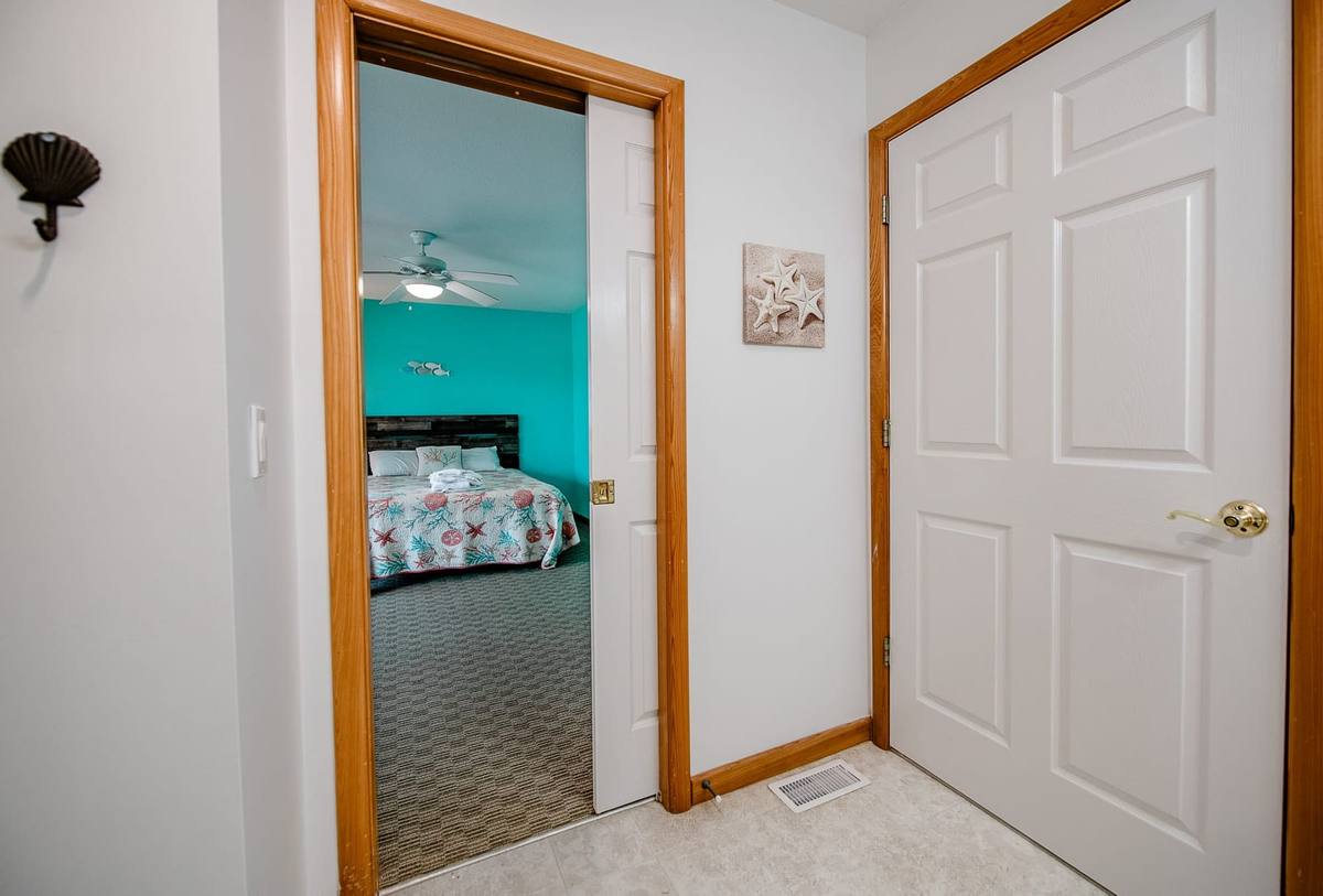 Bathroom doorway with a shell decoration and the teal bedroom beyond