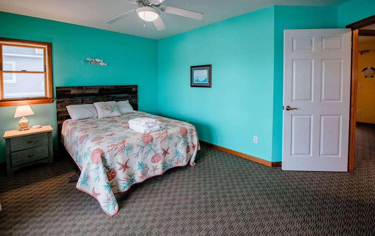 Teal bedroom seen from the door, with a driftwood-style headboard