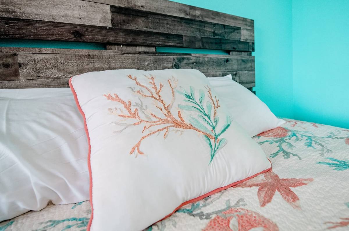 Close view of a coral-print pillow against a driftwood headboard