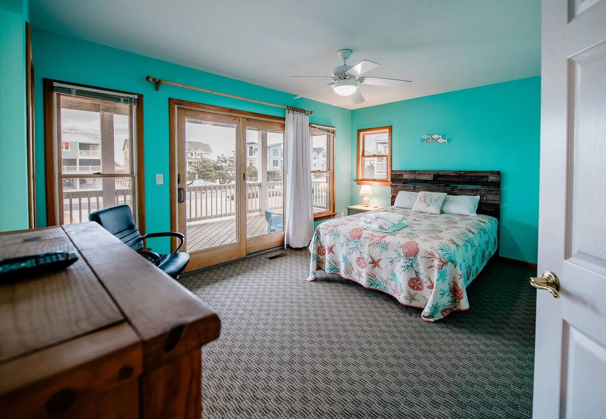 Teal bedroom with a bed, a desk, and glass doors to the deck
