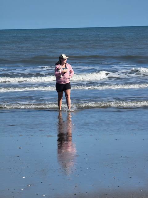 A woman wading and laughing in the surf on an empty beach