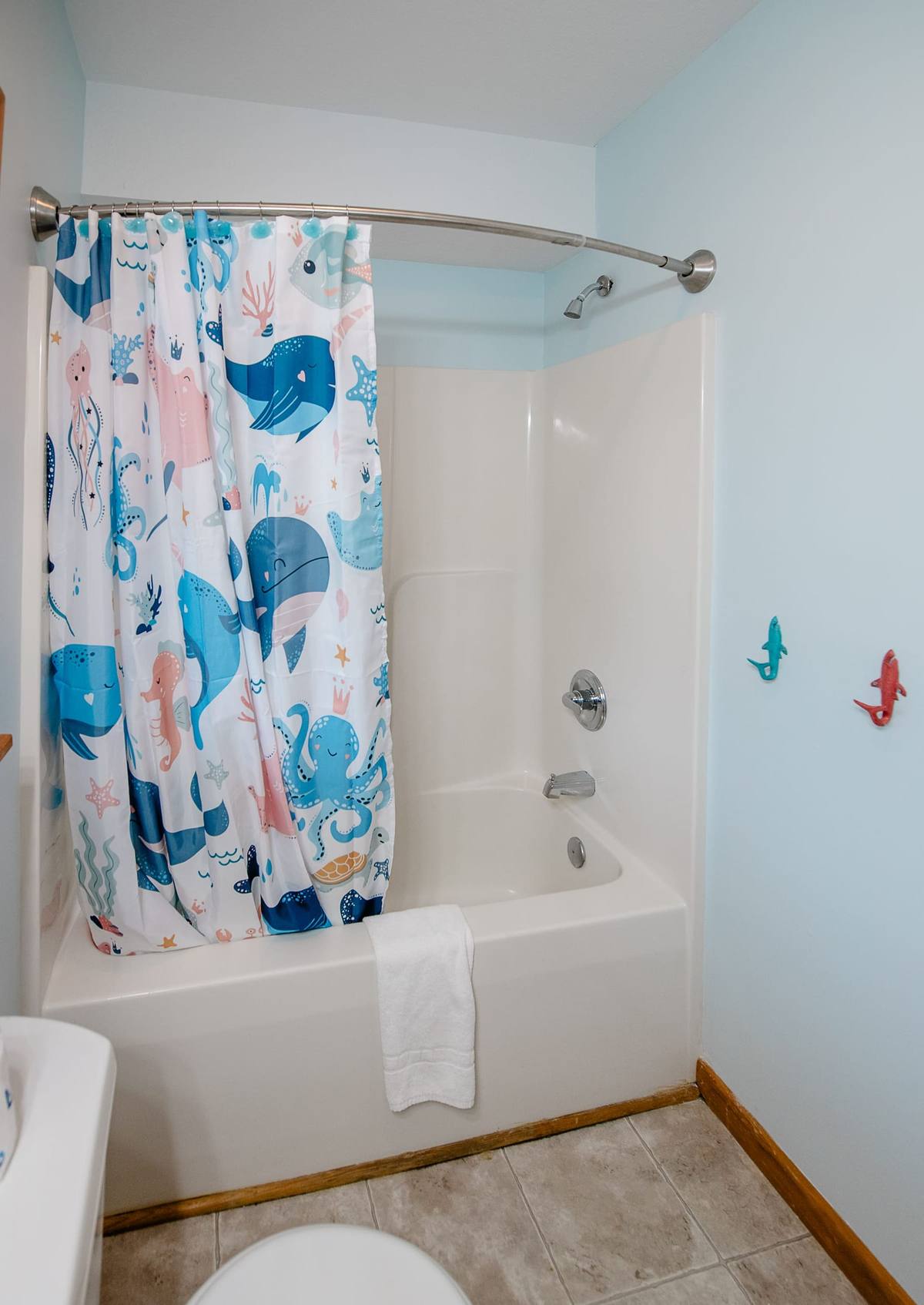 Tub with a shower curtain printed with whales and an octopus