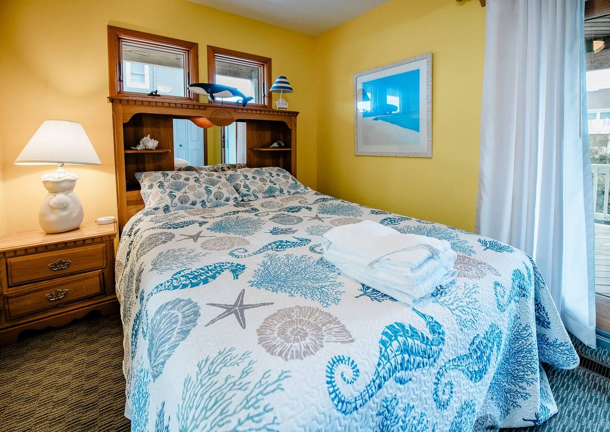 Yellow bedroom with a bed in a seahorse-print quilt and a bookcase headboard
