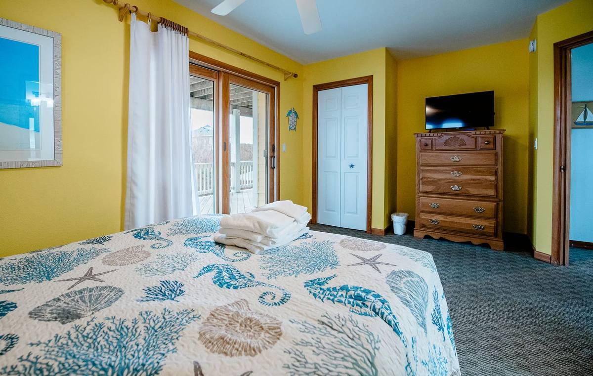 Yellow bedroom with a TV on a dresser and a closet door